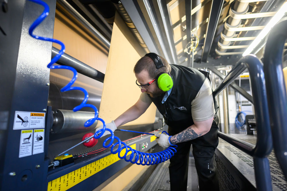 A technician wearing safety gear operates machinery in a manufacturing environment, showcasing hands-on expertise.