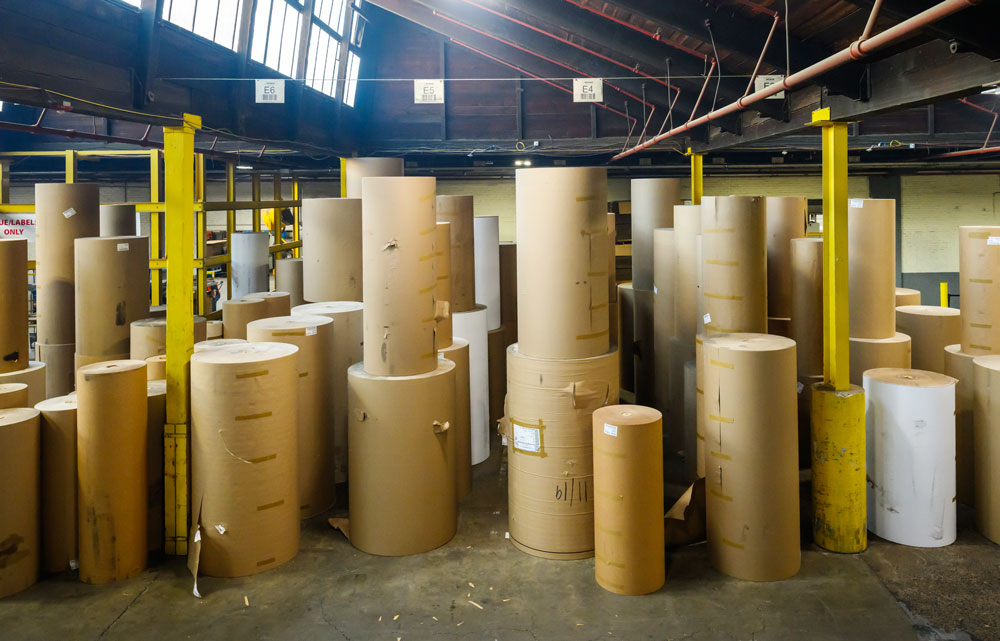 Stacks of large cardboard rolls in a warehouse, highlighting sustainable materials for eco-friendly practices.
