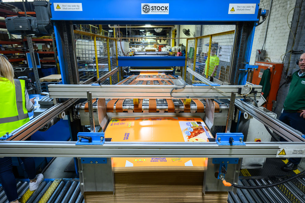 Industrial printing machinery in action, showcasing vibrant printed materials being processed in a manufacturing facility.