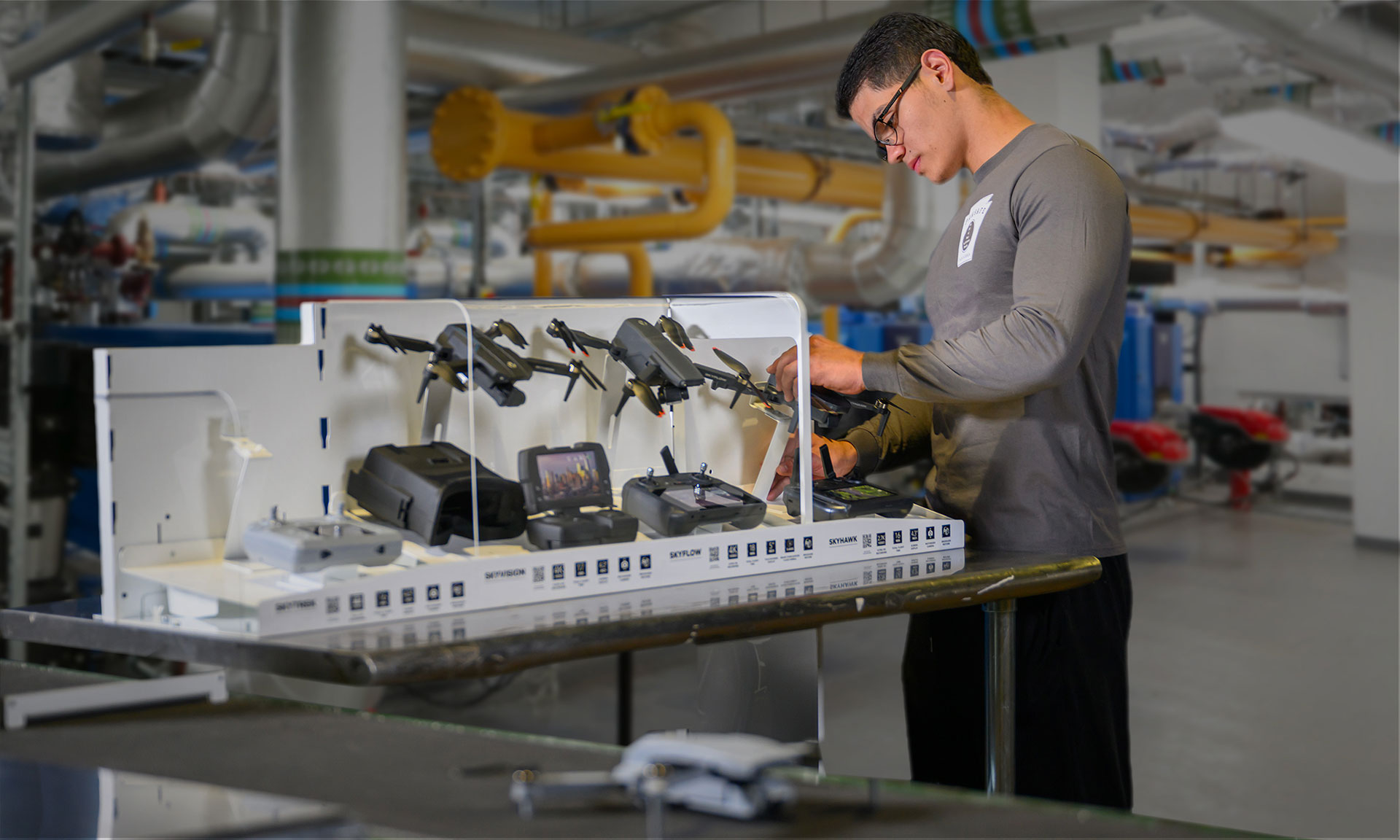 A technician assembles drones on a workstation in an industrial packaging environment.